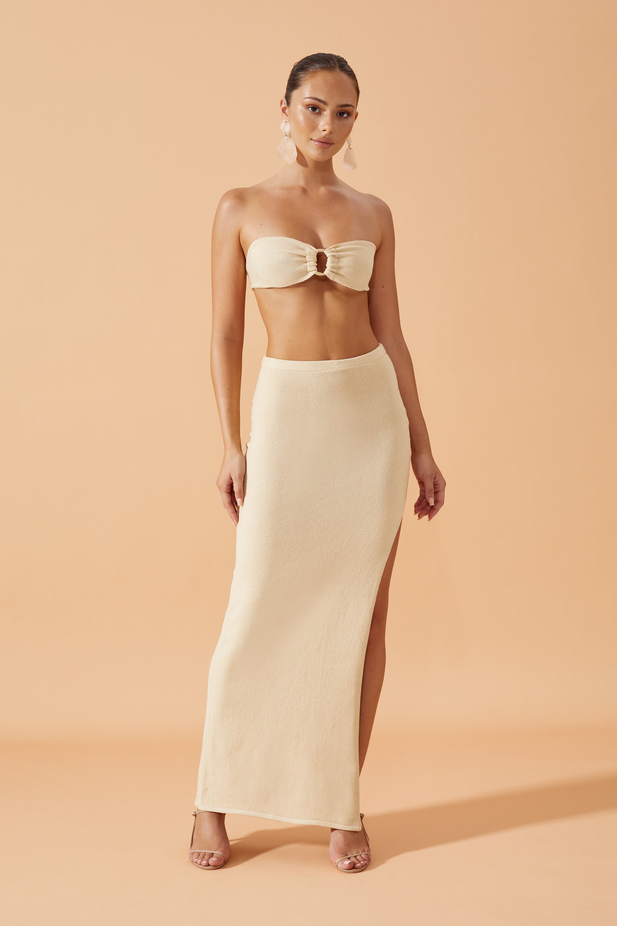 Flook The Label Chika Knit Long Skirt in Sand,with side slit   worn with drop resin earrings, front view