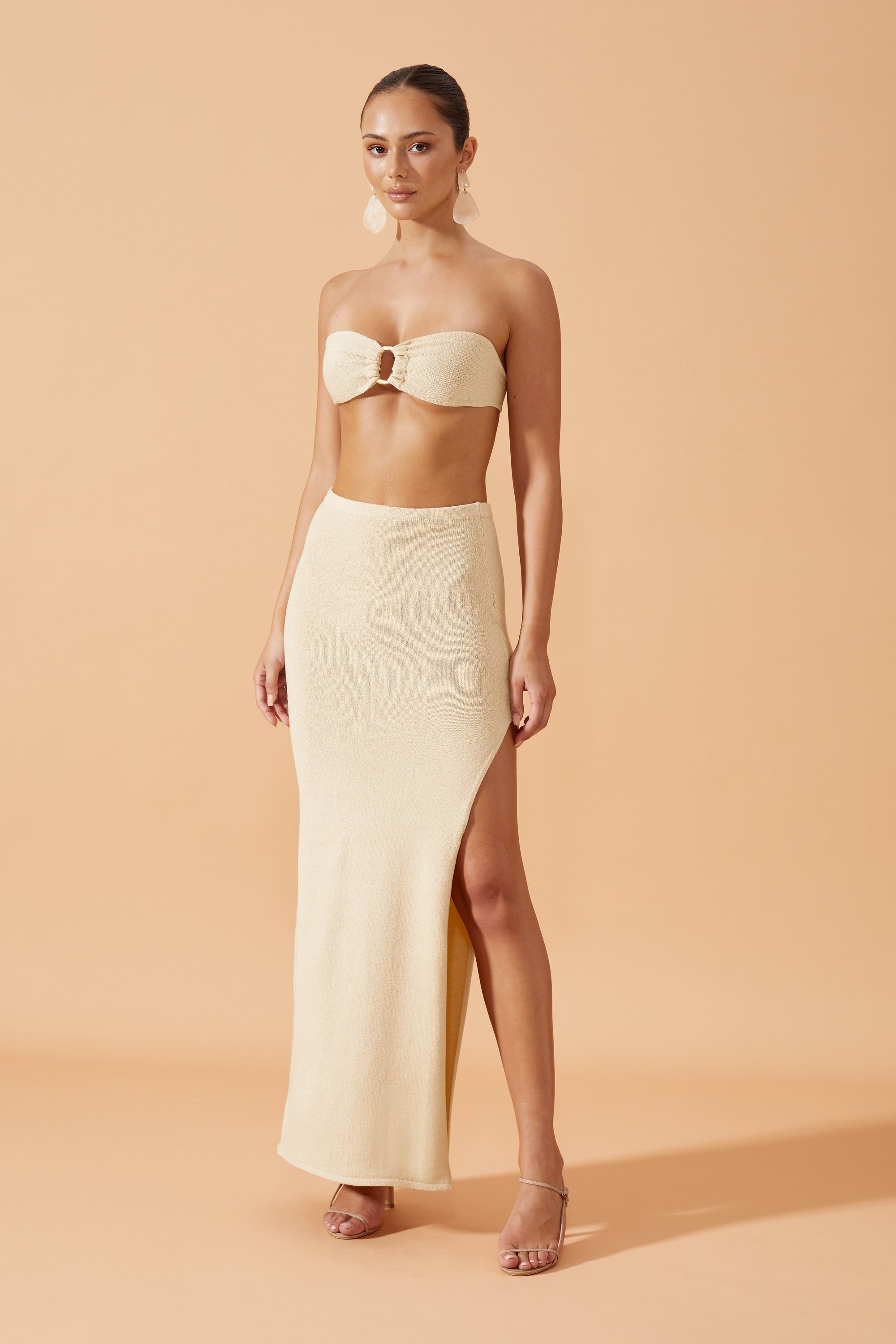 Flook The Label Chika Knit Long Skirt in Sand,with side slit ,  worn with drop resin earrings, front view