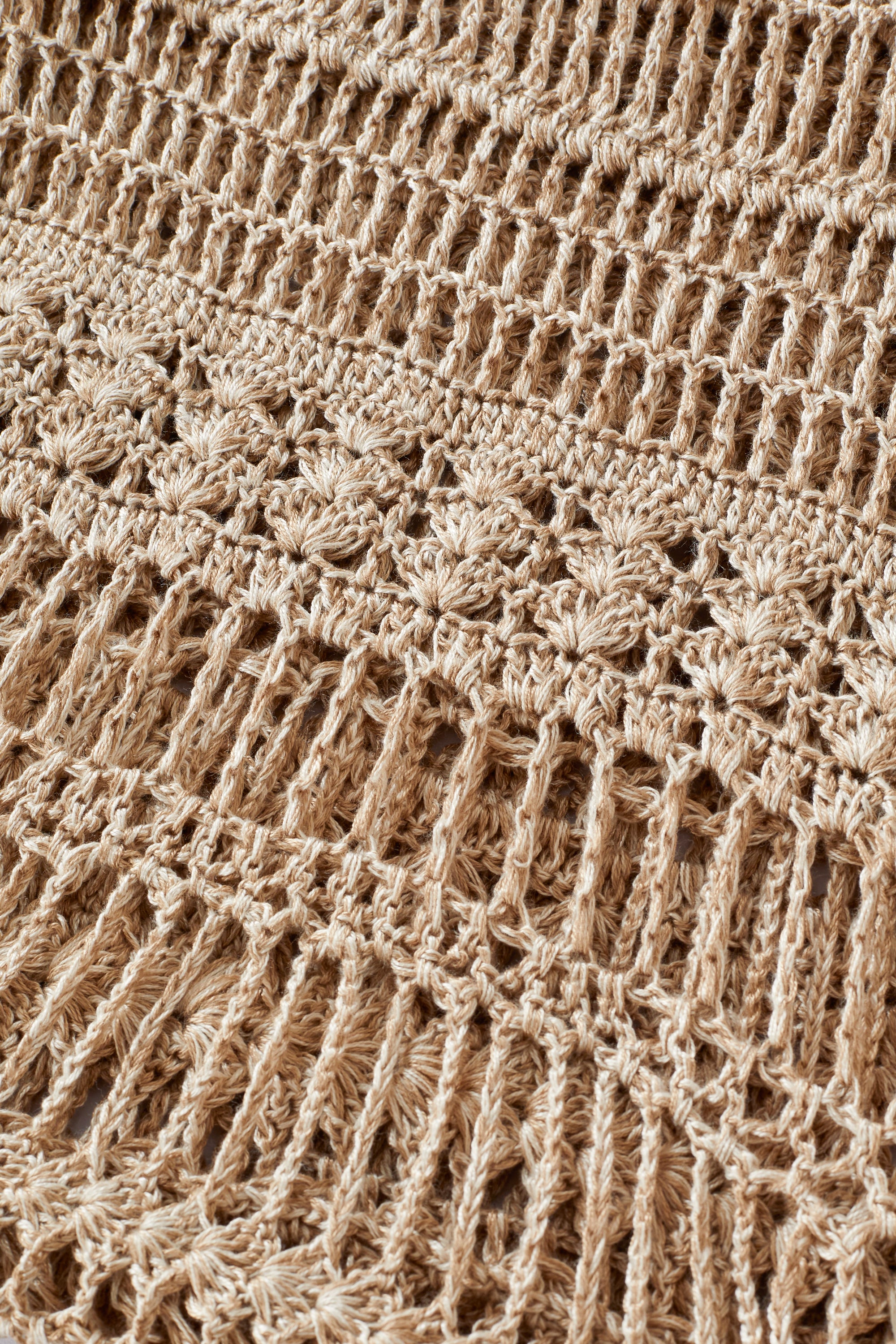 Close-up of beige crochet fabric with intricate pattern