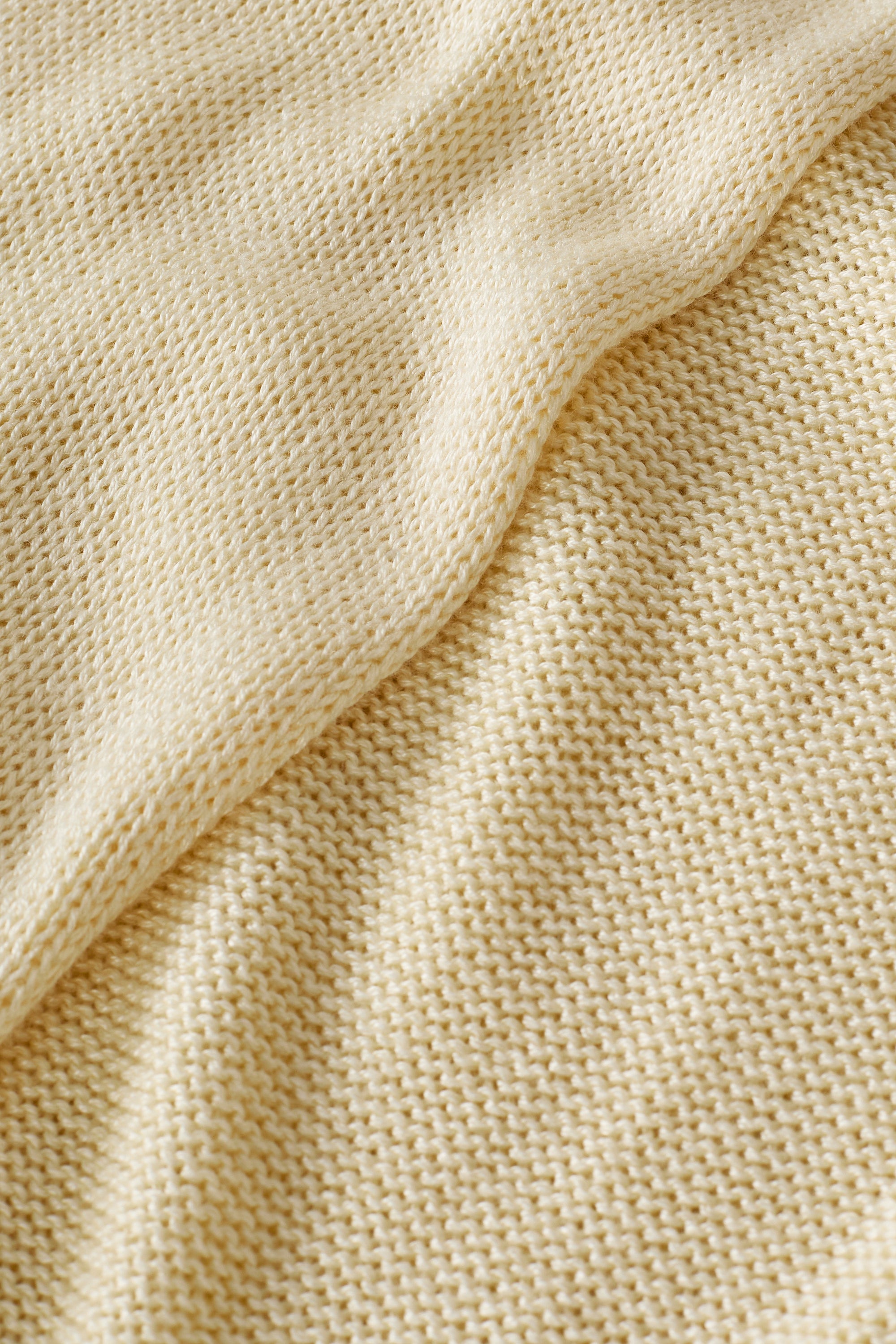 Close-up of the Della Dress’s soft beige knit fabric, featuring visible textured stitches and a gentle diagonal fold.