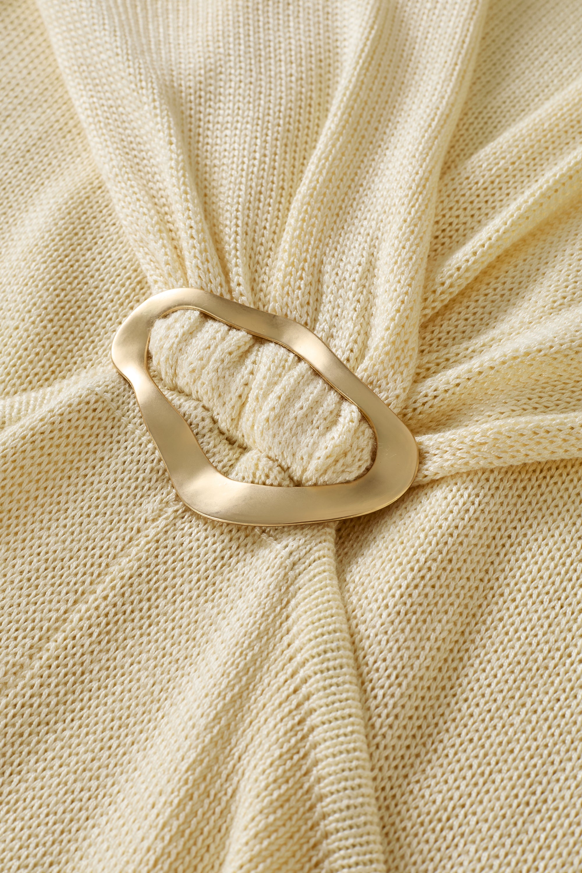 Close-up of cream fabric dress with a gold ring accent