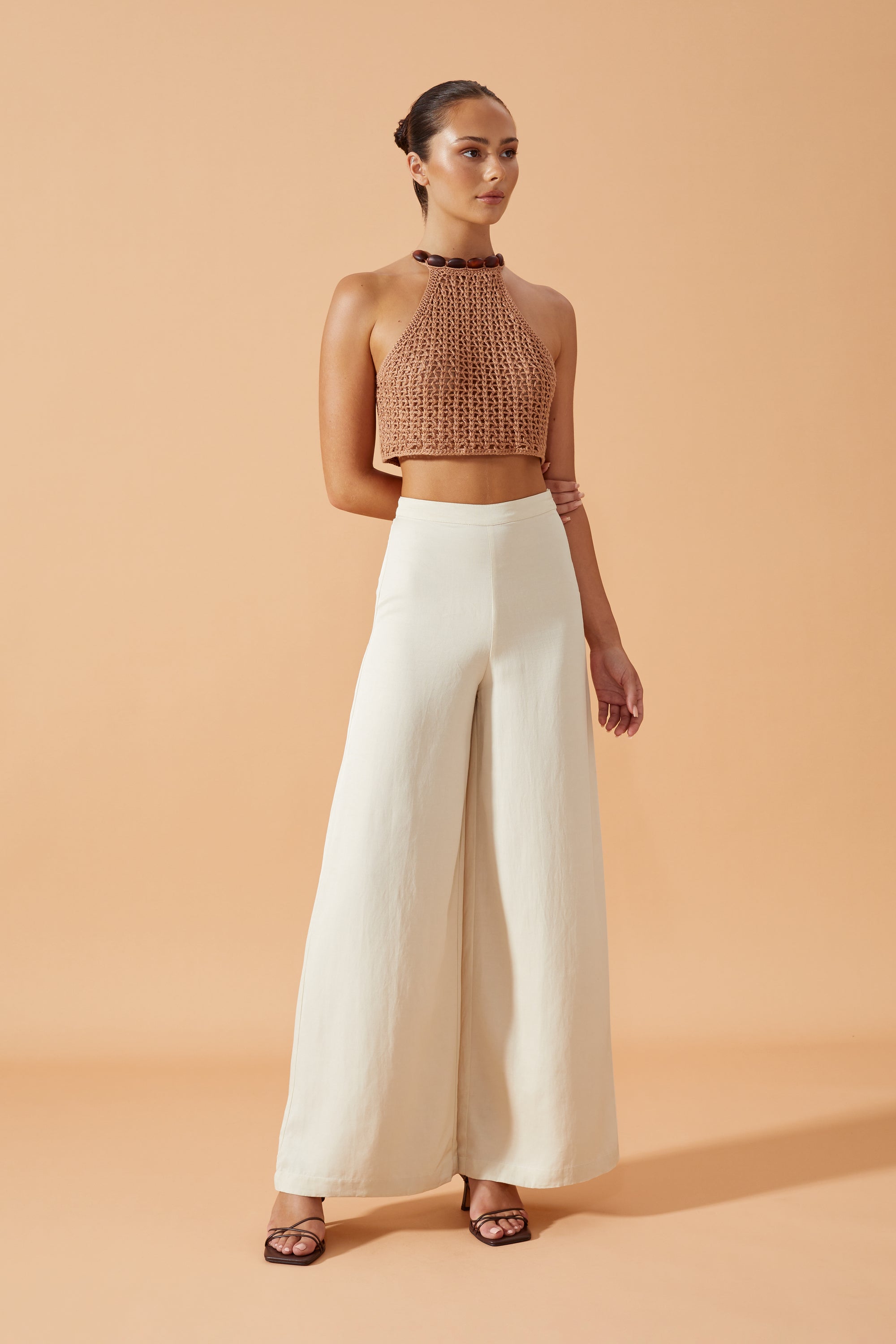 Flook The Label Sonali Crochet Crop Top.  Halter neck embellished by Resin beads. Matched with Zarela Pants in WhiteFront View. 